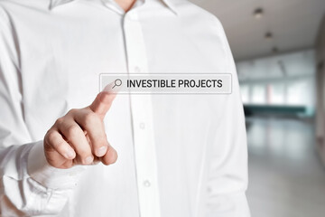 Businessman hand press the search bar on a virtual screen with the word investible projects. Online search for project investment opportunities