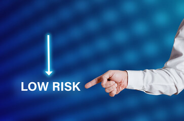 Businessman hand points to the word low risk with arrow icon.