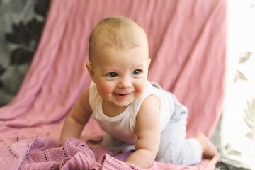 Portrait of a child, a six-month-old baby crawling on the couch and smiling. Childhood and Parenthood concept