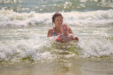 family swims in sea waves on the beach
