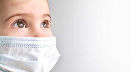 Coronavirus Covid-19. Little child girl wearing protection face medical mask on grey background. Stay home. Social distancing. School kid. Back to school. Banner with place for text