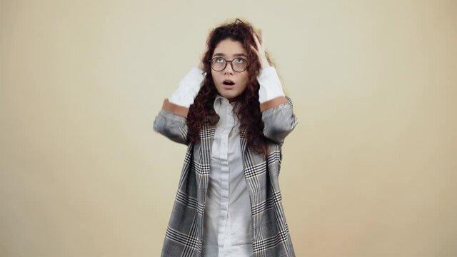 What happened, the shocked young woman, desperate with her hands on her head, asks why. Cretaceous in gray jacket and white shirt, with glasses posing isolated on a beige background in the studio. The