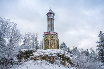 Lookout tower Stepanka on the border of Krkonose and Jizera Mountains. Winter overcast day, sky with clouds, trees covered with snow.