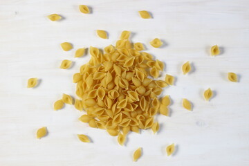 Raw shell shape pasta on white wooden background