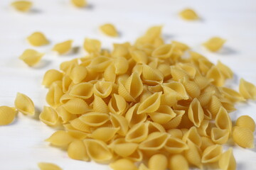 Raw shell pasta on white wooden background