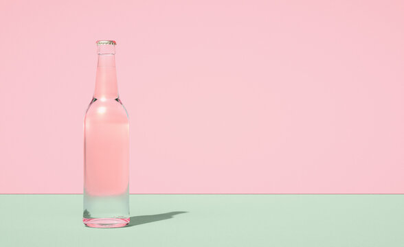 Glass beer bottle on horizontally divided bi-color retro pastel pink and green color background.