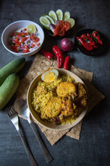 Top view of Chicken biryani or traditional rice with salad ingredients and condiments. 