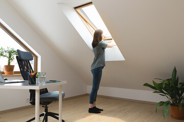 Women opening a window at home office and letting fresh air in. Healthy working environment in new...