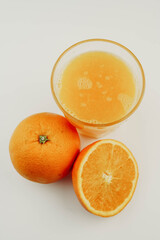 Vaso de zumo de naranja con una naranja y media