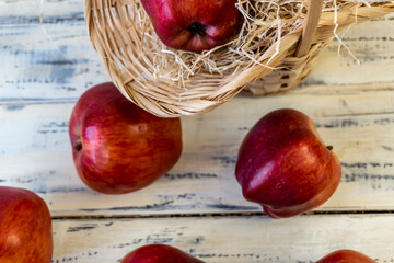 Red apples in a basket and on a wooden table