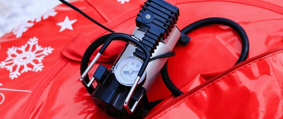 Electric pump with monometer pumping air into tire of tube on winter day. Equipment, device.	