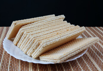 A stack of crisp waffles is on a white plate.