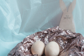 Happy Easter greeting card. In a shiny nest, there are two eggs. A rabbit is hiding behind a nest,...