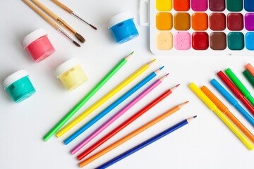 Naklejka premium Layout drawing, paints, brushes, palette, pencils and markers on a white background, top view