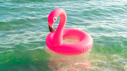 Sea background. Pink inflatable flamingo in blue ocean water for sea summer beach background. Luxury lifestyle travel.