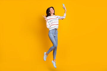 Fototapeta na wymiar Full size photo of young girl happy smile jump up make take selfie show peace cool v-sign isolated over yellow color background
