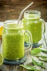 Healthy green smoothie with spinach in glass jars.