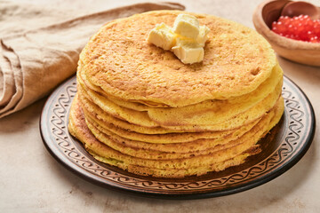 Crepes or thin pancakes stack with butter and red caviar on beautiful ceramic plate on an old brown concrete background. Top view, copy space. Homemade thin crepes for breakfast or dessert.