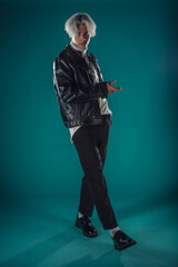 Male beauty concept. Portrait of fashionable young man with stylish haircut wearing trendy glasses and sweater, posing over gray background. Perfect hair & skin. Hipster style. Copy-space. Studio shot