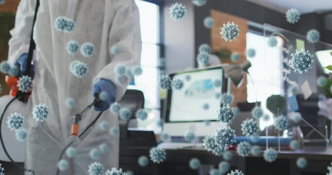 Multiple covid-19 cells floating against male health worker spraying disinfectant at office - Powered by Adobe