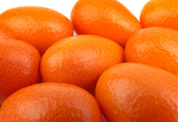 A group of fresh kumquats lies on a white surface.