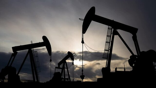 Dawn over petroleum pump, Time Lapse at Sunrise with Fast Clouds and Dark Silhouette of Oil pumpjack