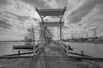 Black and white shot of an pedestrian and bicycle bridge over canal in Reeuwijk, The Netherlands