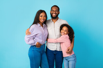 African American man hugging his wife and smiling daughter