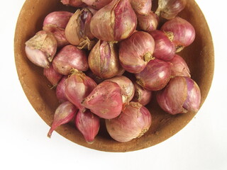 Shallots or red onions in clay plate against white background. One of important spice in Indonesian culinary. 