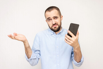 Bearded shows a phone and helpless gesture with arm, not know what to do, white background, copy space