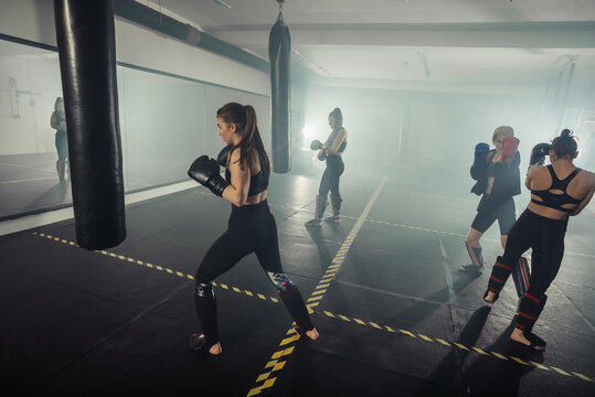 Group of athletic young fit girls in sportswear boxing in gym.