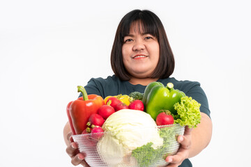 Happy Asian overweight woman holding a vegetable basket and smiling on isolated white background, Concept of good health comes from eating a nutritious diet.