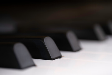 Fototapeta na wymiar Black and white piano keys side view with shallow depth of field. The black keys are called sharps or flats. Focus on the second black key from the left