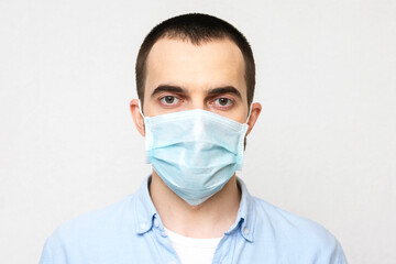 Young man wears a medical mask, white background, portrait, close-up