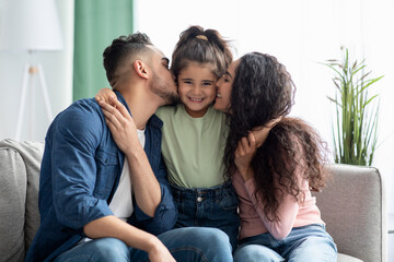 Family Love. Caring Parents Kissing Their Little Daughter, Bonding Together At Home