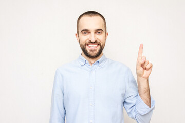 Fototapeta premium Handsome bearded raises his index finger, man has an insight or a good idea, a white background, copy space