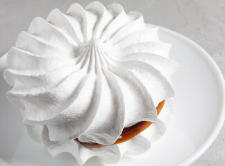 Beautiful white meringue on a white plate. White cake.