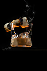 A glass of Irish Cream Liquor with ice cubes and garnished with burning caramelised marshmallow