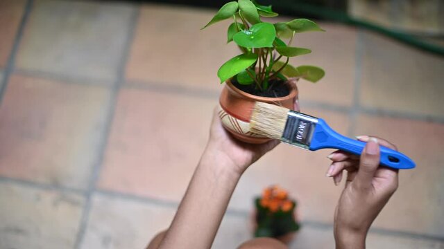 Unrecognizable young black woman varnishes flowerpot after gardening