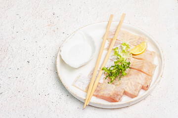 Pieces of raw hake. Fresh fish, lemon wedge, herbs, sea salt