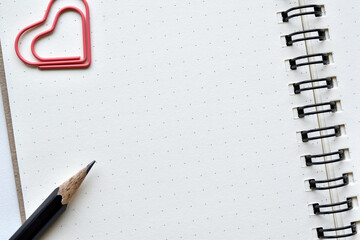 Top view, Dots book for designers to design new ideas with heart paper clip and black pencil is...
