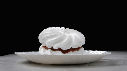 Two snow-white meringues on a white plate. Beautiful white cake.