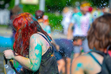 Fototapeta na wymiar girls splashing in the city fountain at the Paint festival.