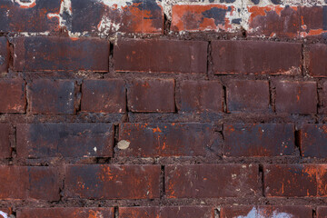 Aged burgundy brick wall texture with traces of paint