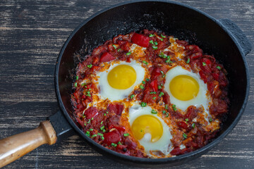 Shakshuka, fried eggs with tomatoes, onion, red pepper and spices in cast iron pan