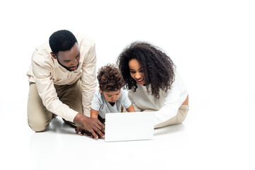 african american couple using laptop together with toddler son on white