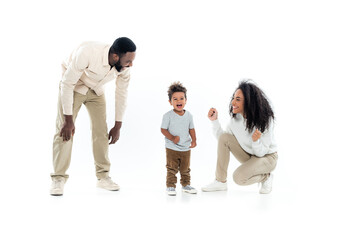 excited african american woman showing win gesture near amazed son and happy husband on white