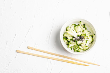 Fresh cucumber salad with sesame seeds in a white ceramic bowl
