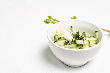 Fresh cucumber salad with sesame seeds in a white ceramic bowl