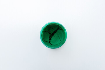 Jar of dried green gouache paints, top view, close-up, white background, copy space .